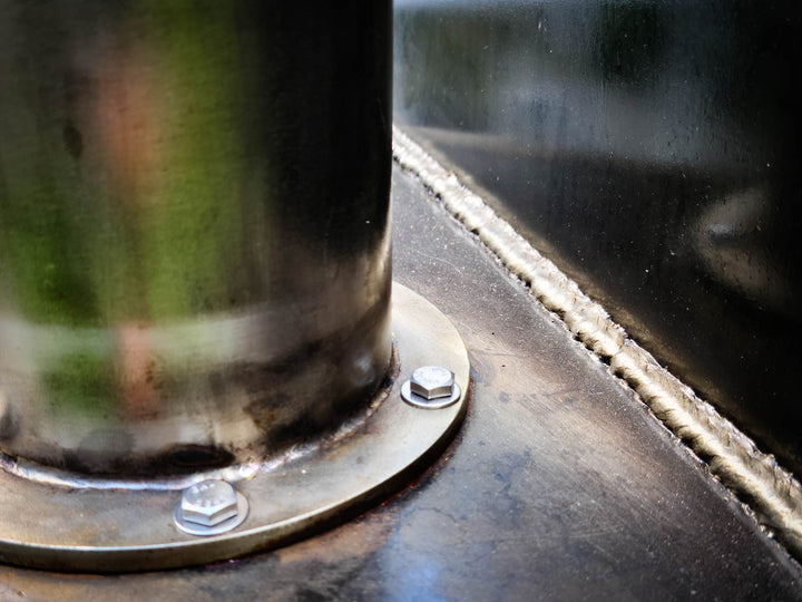 A stainless steel offset smoker smokestack shown connected to to a cook chamber using a stainless steel flange and hardware